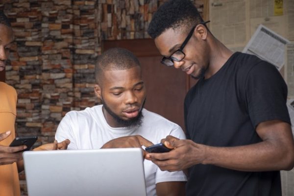 group-young-african-males-discussing-project-while-using-their-laptop-phones_181624-43208